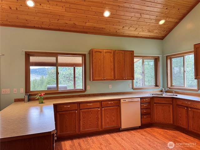 kitchen with a sink, brown cabinets, light countertops, and white dishwasher