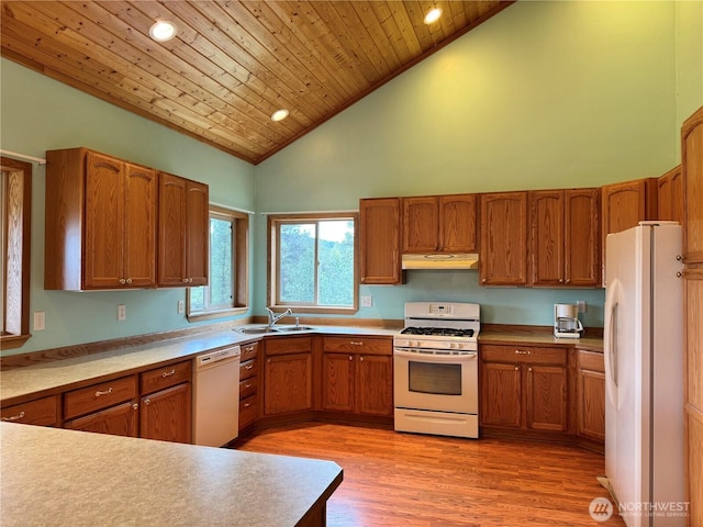 kitchen featuring white appliances, brown cabinetry, under cabinet range hood, a sink, and high vaulted ceiling