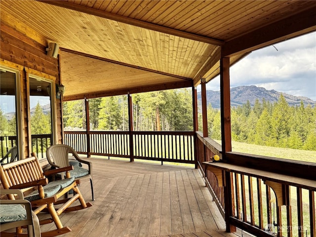 wooden terrace with a wooded view and a mountain view