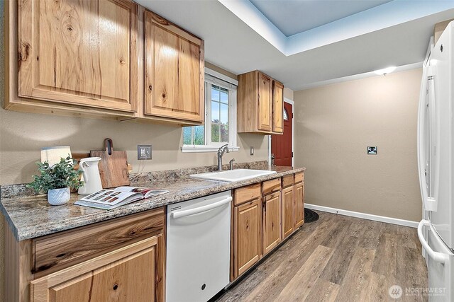 kitchen with white appliances, baseboards, a sink, and light wood-style flooring