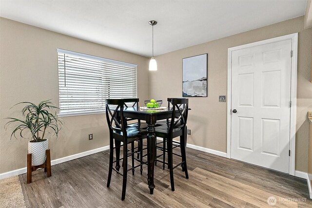 dining area with baseboards and dark wood finished floors