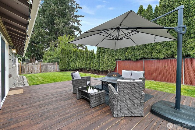 wooden deck with a fenced backyard, a yard, and an outdoor fire pit