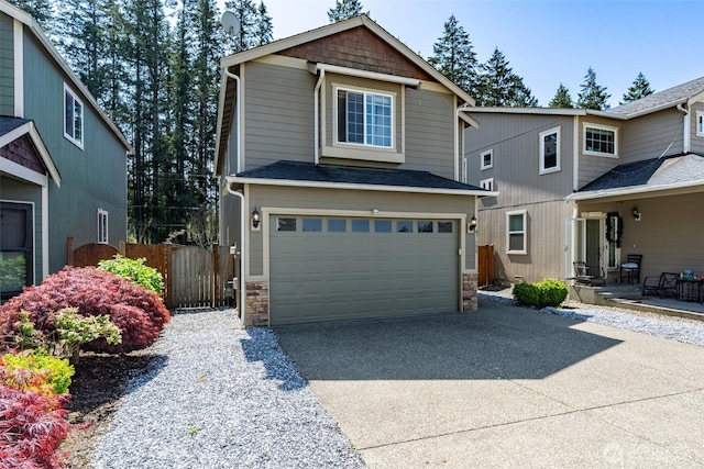 view of front of property with fence, concrete driveway, stone siding, and a garage