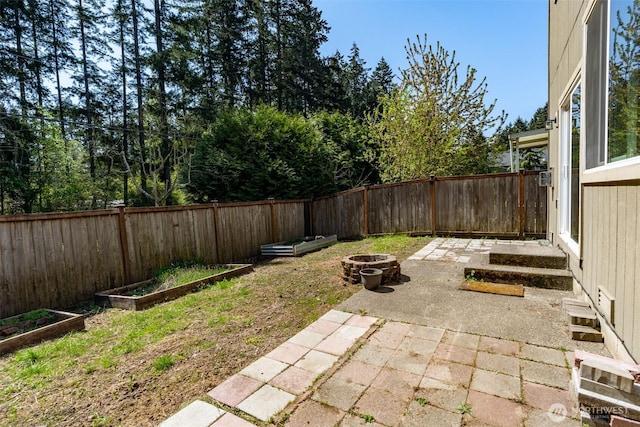 view of yard with a fire pit, a patio area, a fenced backyard, and a garden