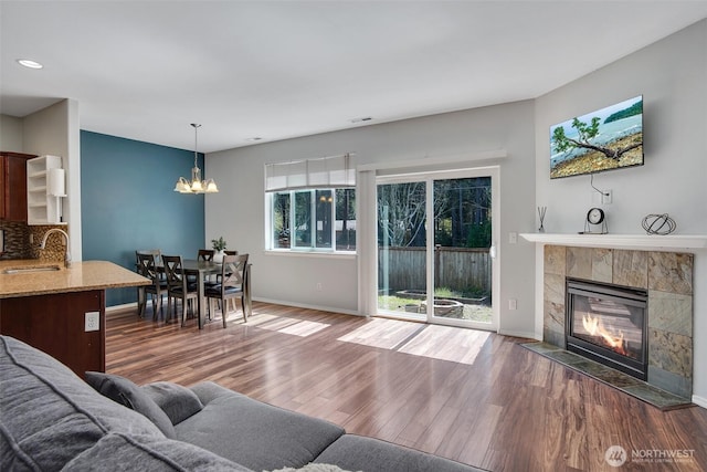 living room with a tile fireplace, visible vents, wood finished floors, and a chandelier
