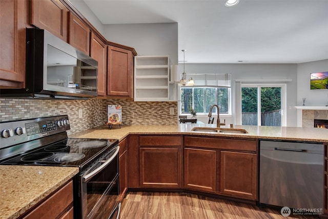 kitchen with light stone countertops, open shelves, appliances with stainless steel finishes, backsplash, and a sink