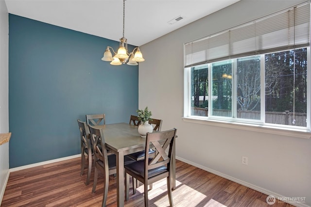 dining room with a notable chandelier, visible vents, wood finished floors, and baseboards
