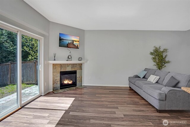 living room featuring wood finished floors, a tiled fireplace, and baseboards