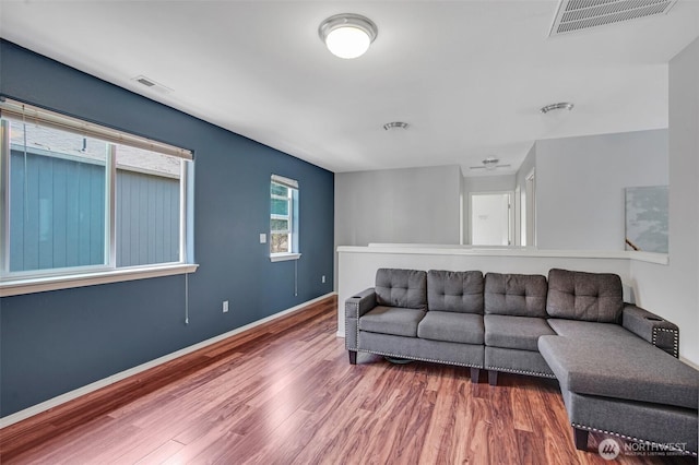 living area with visible vents, wood finished floors, and baseboards