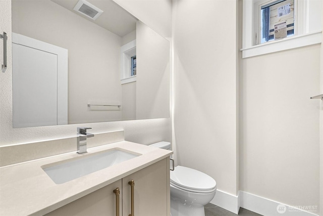 half bath with tile patterned floors, visible vents, vanity, and toilet