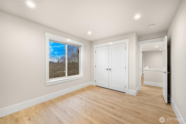 unfurnished bedroom featuring recessed lighting, baseboards, a closet, and light wood-type flooring