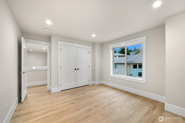 unfurnished bedroom featuring baseboards, recessed lighting, light wood-style floors, and a closet