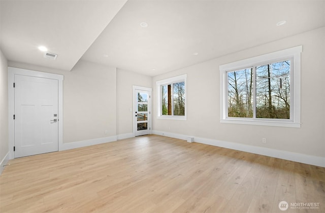 spare room featuring light wood-type flooring, visible vents, and baseboards
