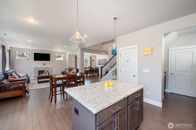 24524 96th Ave S, Kent, WA 98030 - kitchen with dark wood-style floors, open floor plan, pendant lighting, a stone fireplace, and dark brown cabinetry