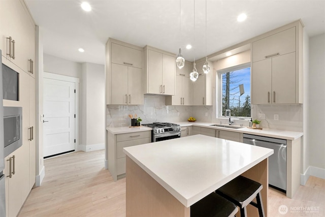 kitchen with stainless steel appliances, a sink, light wood-type flooring, baseboards, and decorative backsplash