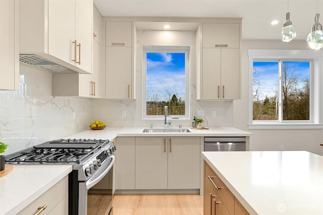 kitchen with tasteful backsplash, a sink, pendant lighting, stainless steel appliances, and light countertops