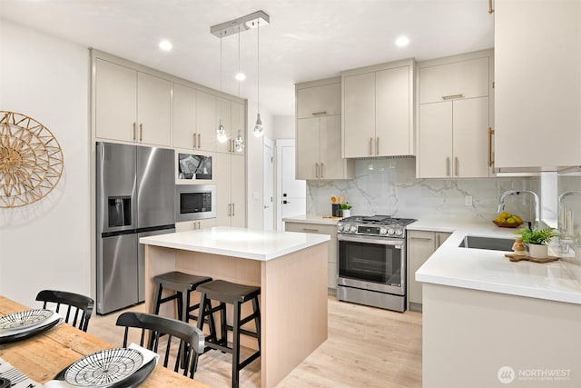 kitchen featuring a sink, decorative backsplash, a kitchen bar, appliances with stainless steel finishes, and a kitchen island