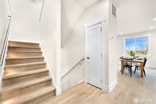 staircase featuring baseboards, wood finished floors, visible vents, and recessed lighting