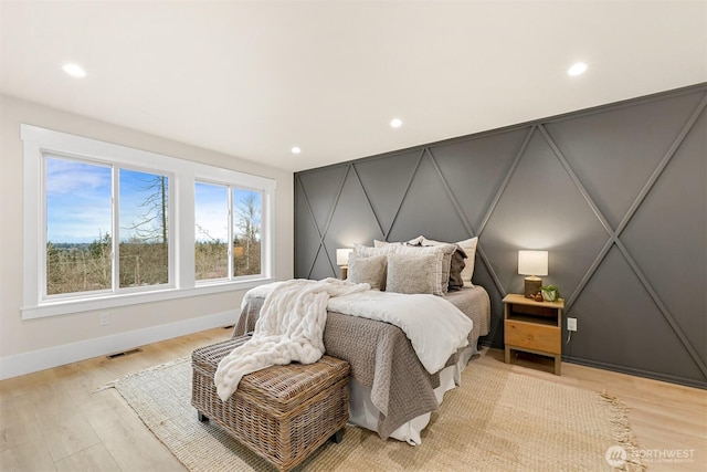 bedroom with baseboards, a decorative wall, visible vents, and recessed lighting