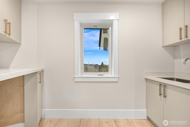 interior space with light wood-type flooring, baseboards, and a sink