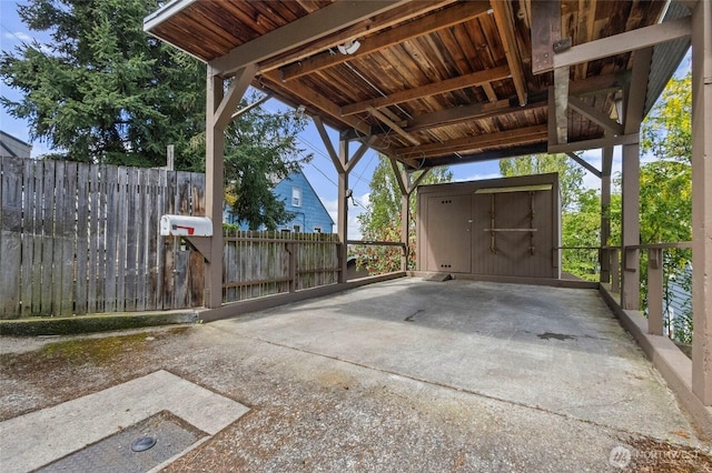 exterior space featuring an outdoor structure, fence, a shed, and a carport