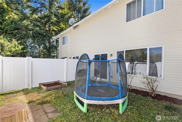 view of yard featuring a trampoline and fence