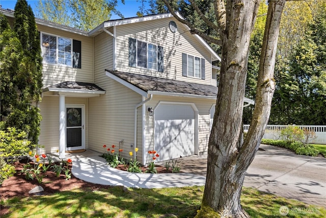 traditional-style home featuring concrete driveway, an attached garage, and fence
