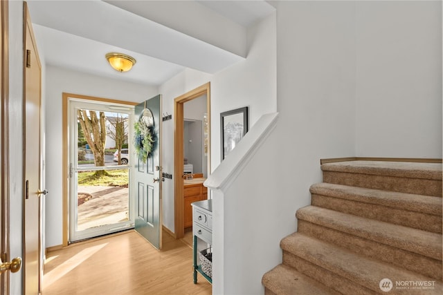 foyer featuring stairs, baseboards, and light wood-style floors
