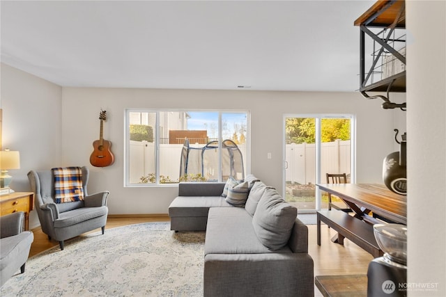 living room featuring baseboards, wood finished floors, a healthy amount of sunlight, and visible vents