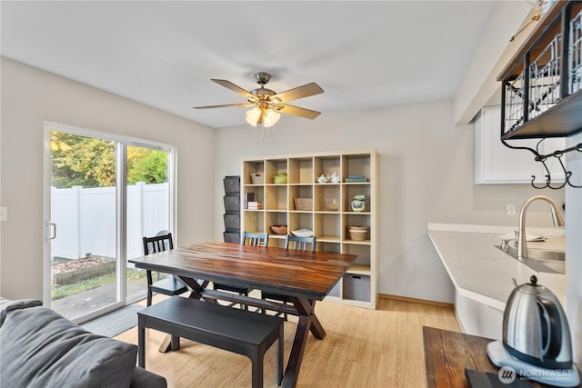 dining space featuring baseboards, ceiling fan, and light wood finished floors