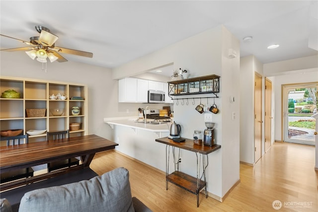 interior space with light wood-style floors, white cabinets, stainless steel microwave, and range
