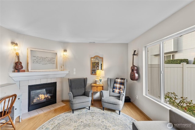 sitting room featuring a tiled fireplace and wood finished floors