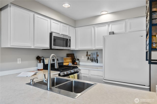 kitchen with light countertops, a sink, stainless steel appliances, recessed lighting, and white cabinetry