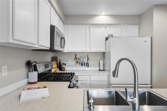 kitchen with light countertops, white cabinetry, appliances with stainless steel finishes, and a sink