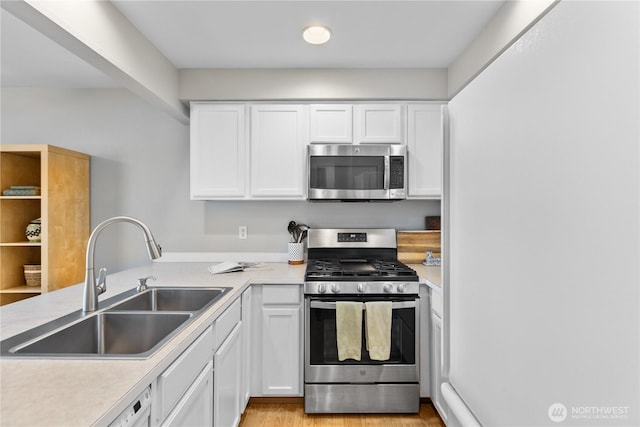 kitchen with a sink, appliances with stainless steel finishes, white cabinets, and light countertops