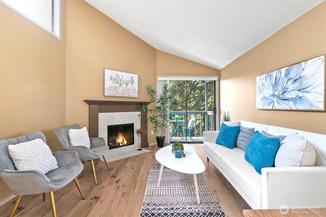 living area with a fireplace, a textured ceiling, wood finished floors, and high vaulted ceiling