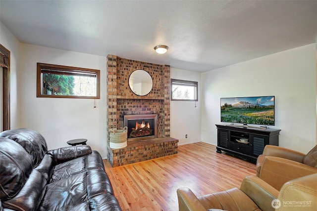 living room featuring a brick fireplace and wood finished floors