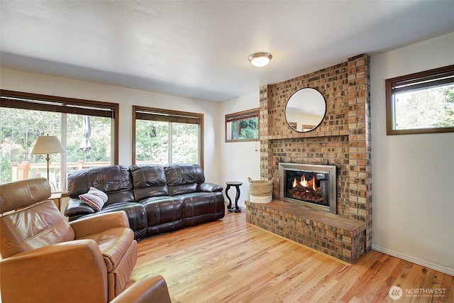 living area featuring baseboards, a fireplace, and light wood-type flooring