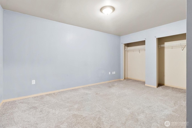 unfurnished bedroom featuring carpet floors, baseboards, and multiple closets
