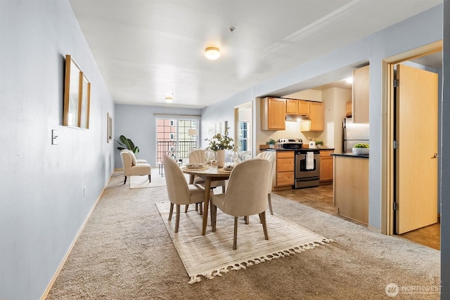 dining room with baseboards and light carpet