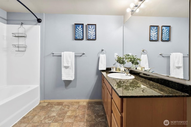 full bath with baseboards, stone finish flooring, bathtub / shower combination, and vanity