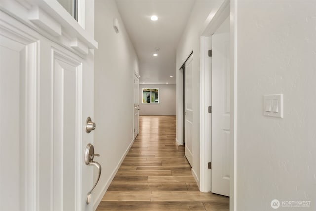 corridor with light wood-type flooring, recessed lighting, and baseboards