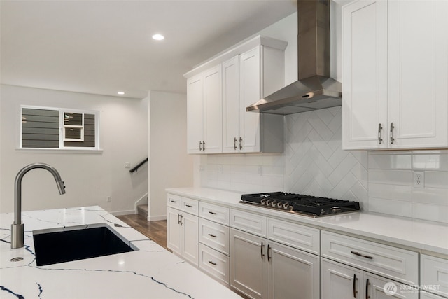 kitchen with wall chimney range hood, tasteful backsplash, a sink, recessed lighting, and stainless steel gas cooktop
