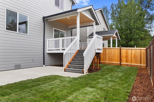 property entrance with fence, a patio area, a yard, and a wooden deck