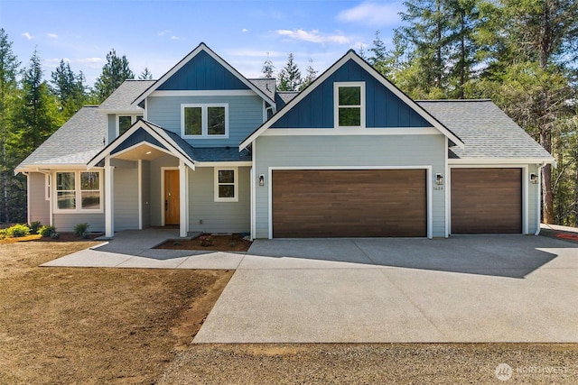 craftsman-style home featuring an attached garage, driveway, roof with shingles, and board and batten siding