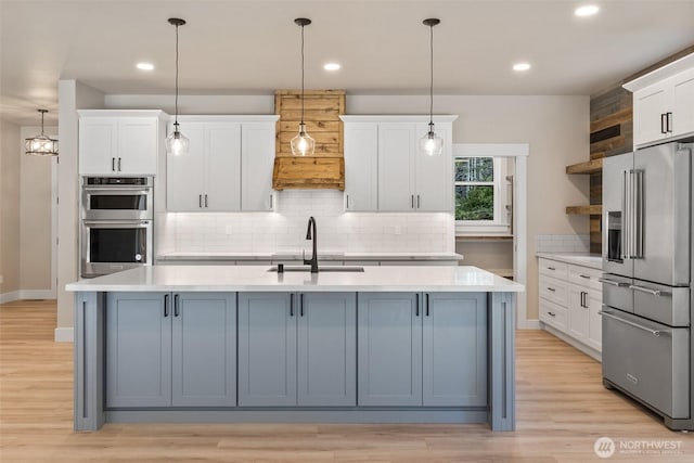 kitchen featuring open shelves, light countertops, stainless steel appliances, and a sink