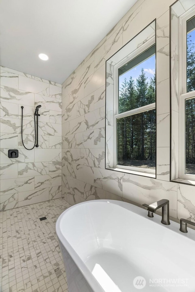 full bath featuring tile walls, a freestanding tub, recessed lighting, and tiled shower