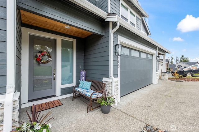 view of exterior entry featuring a porch, driveway, and a garage