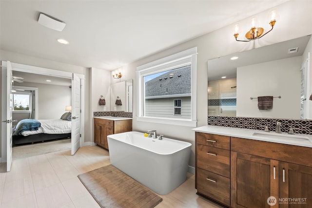 ensuite bathroom with a freestanding bath, a sink, two vanities, ensuite bathroom, and backsplash