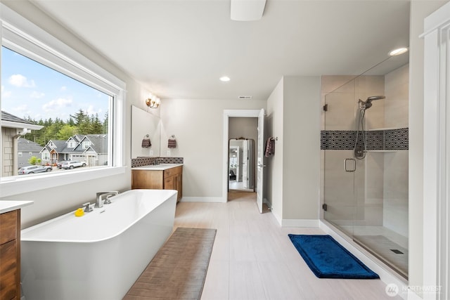 full bath with a freestanding tub, vanity, a stall shower, and recessed lighting